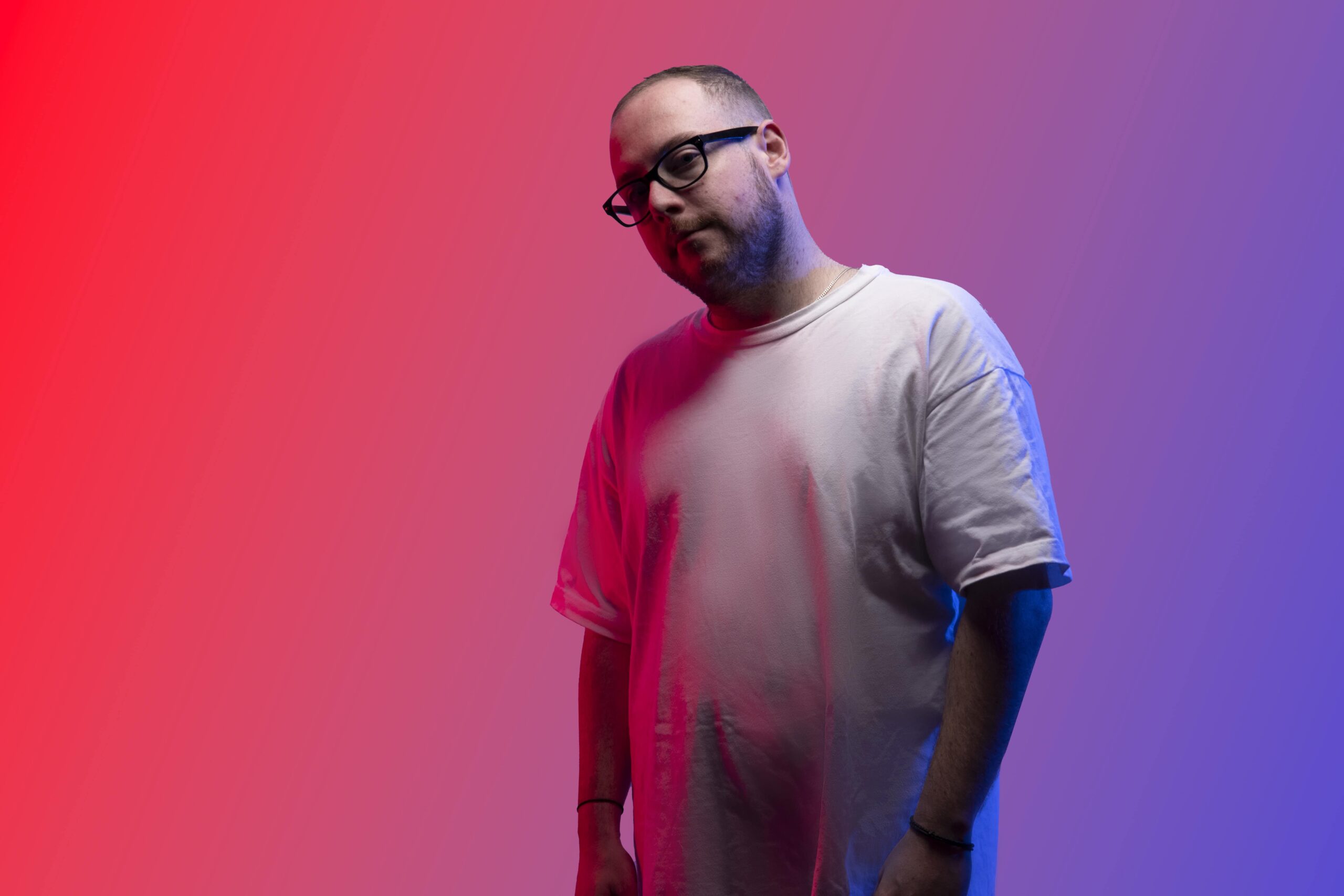 A man in glasses standing in front of a red and blue background. Professional Headshot Photography Melbourne, Crayluxmedia