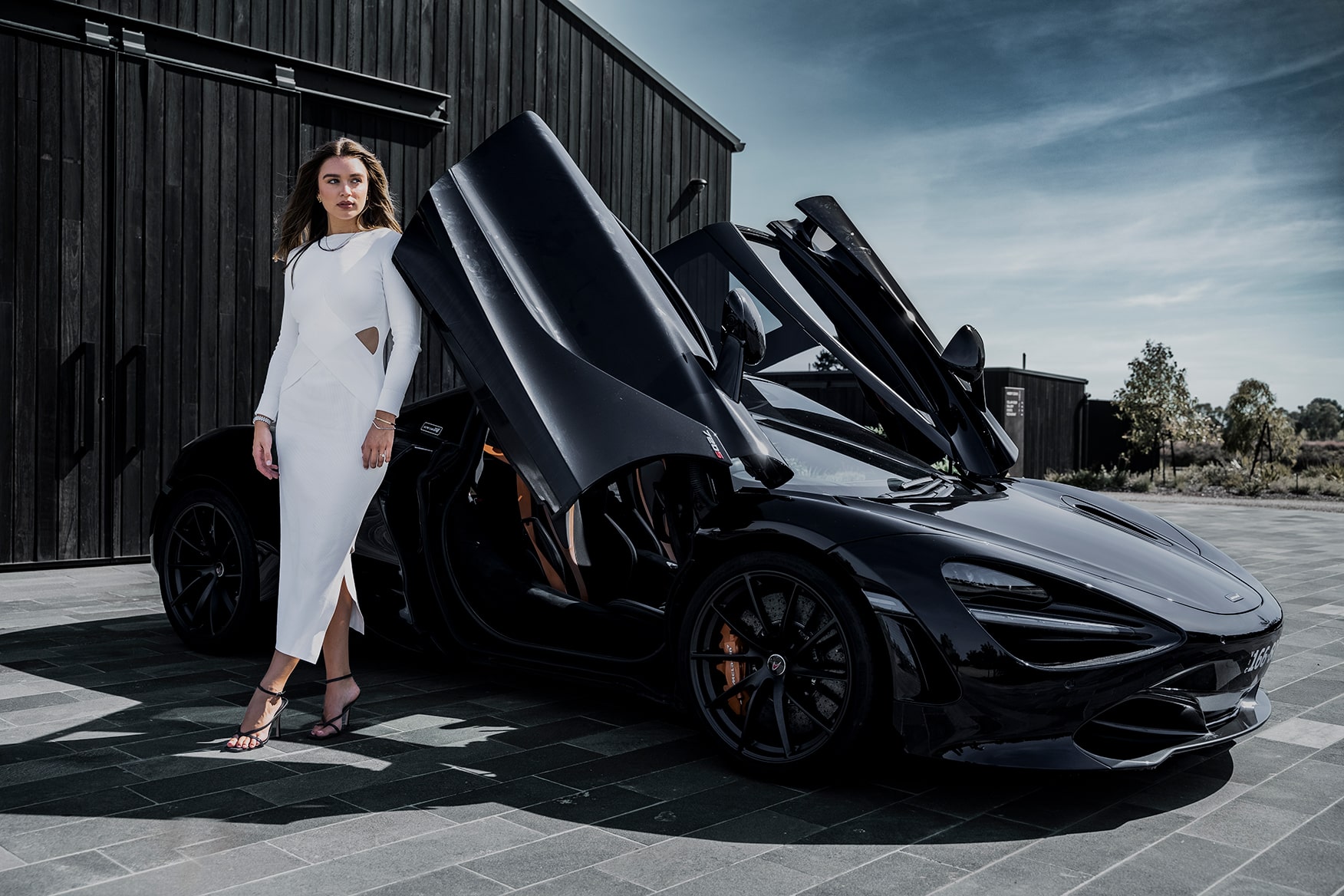 Professional Brand Promo Photographer Melbourne captures woman in white by black sports car