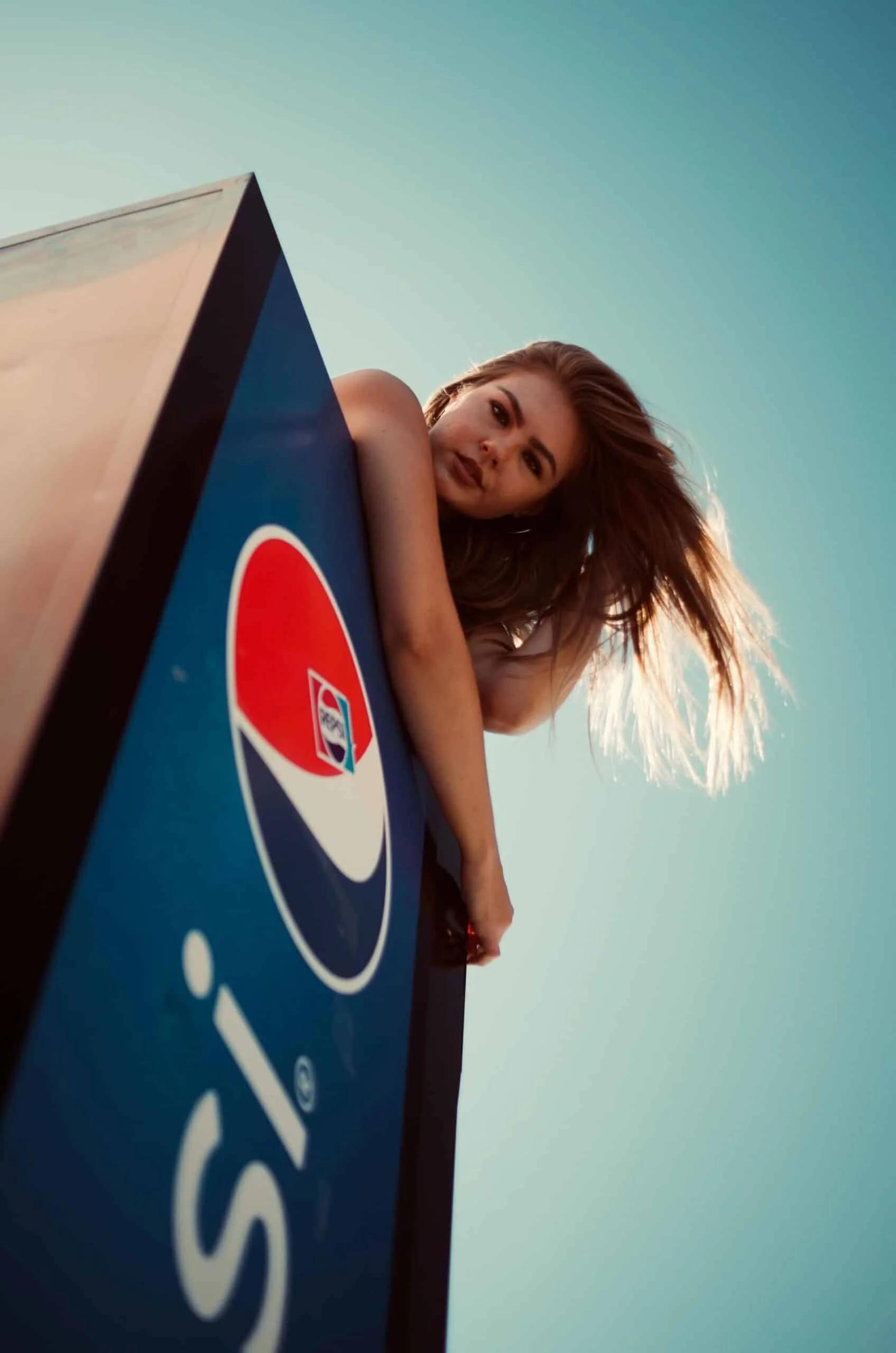 Low Angle Photo of Woman on Top of Pepsi Fridge Posing
